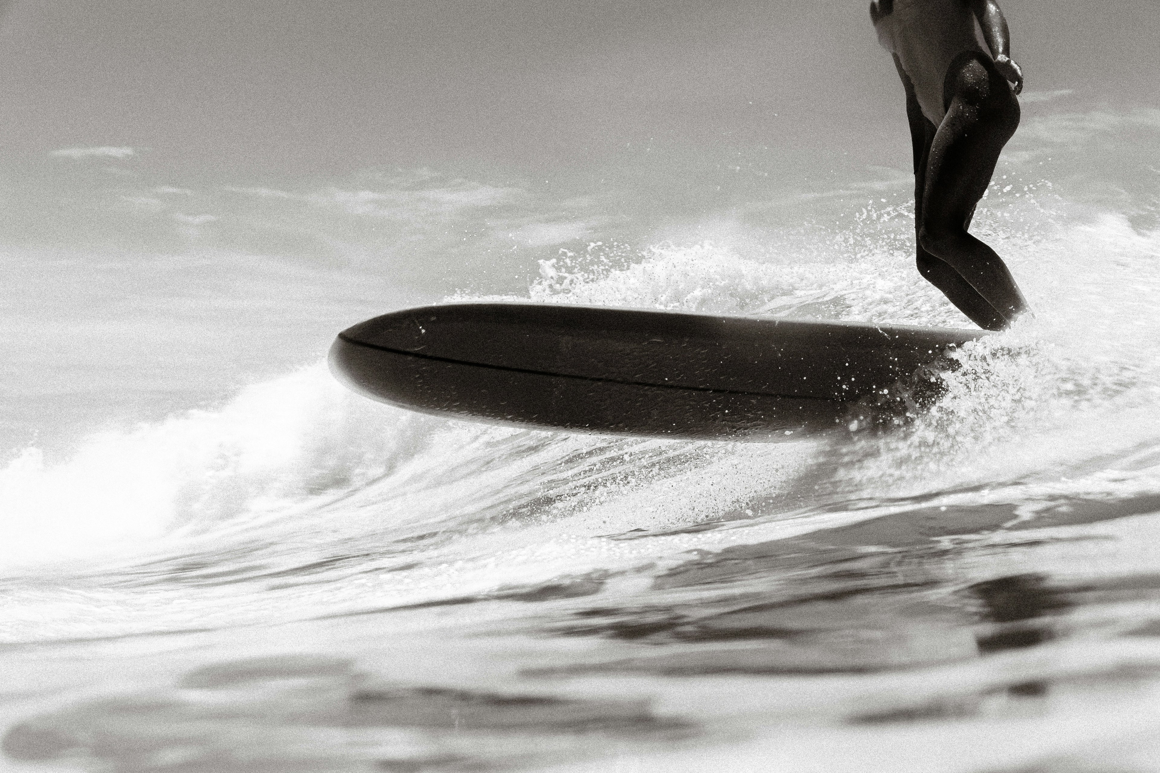 female surfer riding a wave on a longboard in black and white
